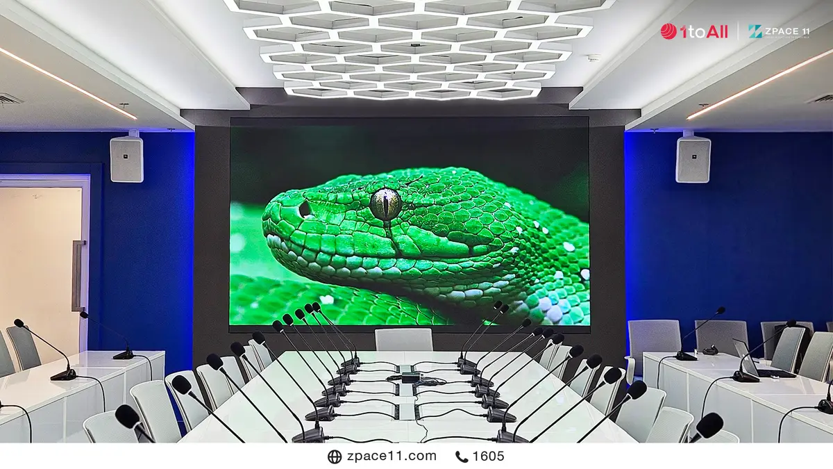 ห้องประชุมใหญ่ที่มีจอ LED แสดงภาพงู ลำโพงติดผนังสองข้างและไมโครโฟนตั้งโต๊ะ