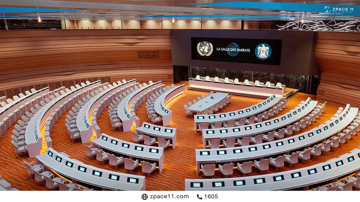 ห้องประชุมใหญ่ที่มีจอ LED เหนือเวทีแสดงสัญลักษณ์สหประชาชาติ