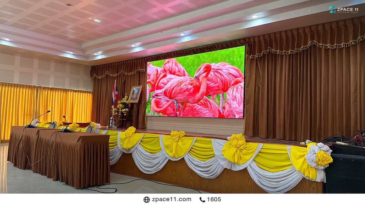 จอ LED บนเวทีห้องประชุมของเทศบาลที่ตกแต่งด้วยผ้าสีเหลืองและสีขาว