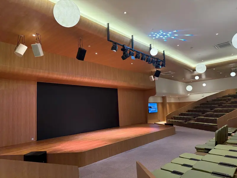 เวทีหอประชุมที่มีจอ LED ขณะปิด ลำโพงแขวน ราวไฟเวที และที่นั่งแบบขั้นบันได