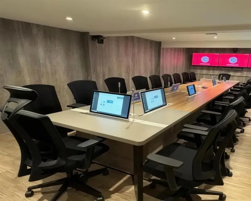 ห้องประชุมผู้บริหารที่มีจอไร้กระดาษแบบยกขึ้นและไมค์คอห่านทุกที่นั่ง จอวิดีโอวอลล์สามจอ และกล้องติดเพดาน